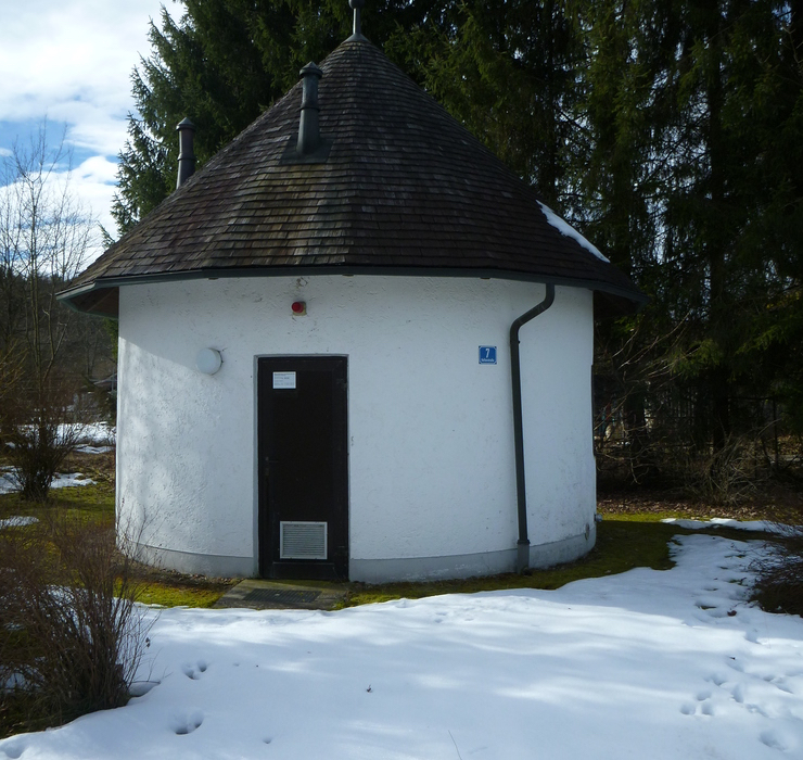 Ortskanal Chieming Ortskanal Chieming. Ein weißes kleine Rundes gebäude mit Kegelförmigem Holzdach. Am Gebäude rechts ein blaues Schild mit der Zahl 7. Vor dem Gebäude liegt noch Schnee.