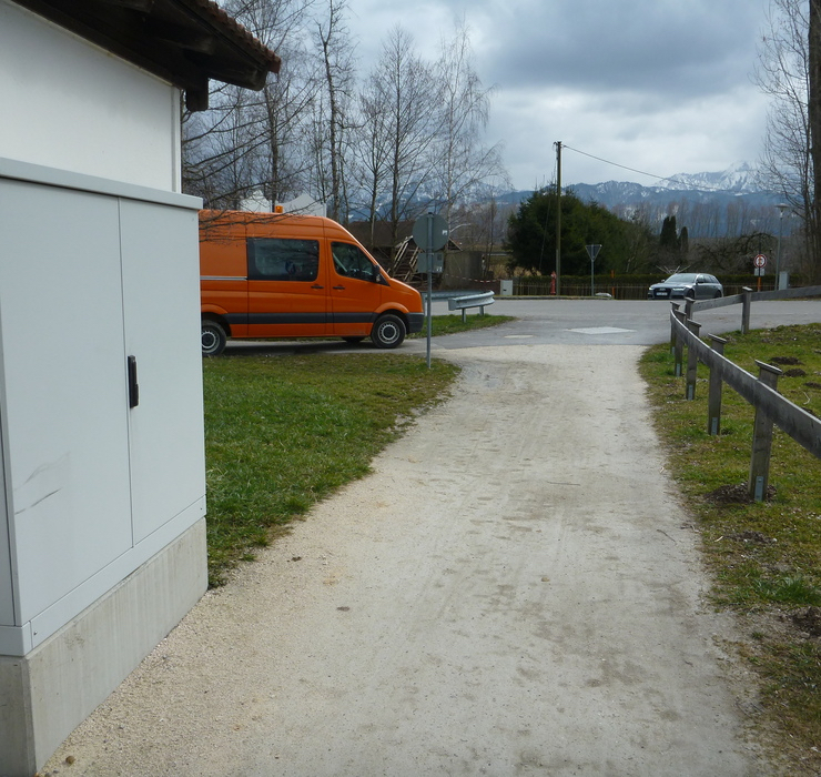 Ortskanal Betreuung Gemeinde Übersee Ortskanal Betreuung Gemeinde Übersee. Ein geschotterer Weg. Rechts durch einen Holzzaun begrenzt, Links ein Stromverteilerkasten. Ebenfalls auf der Linken Seite weiter vorne ein Roter Kastenwagen der Stadt